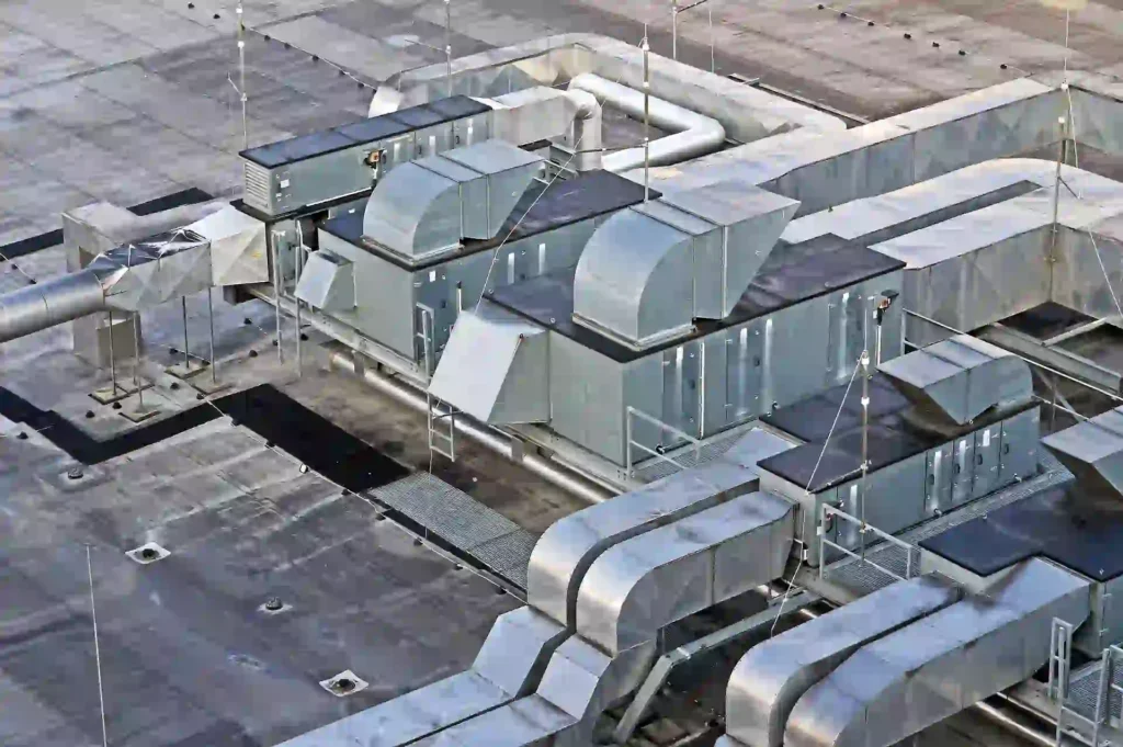 Aerial view of large HVAC ductwork and mechanical units mounted on a flat commercial roof membrane.