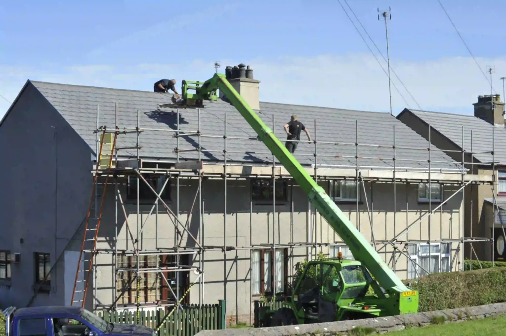 Pre-Listing Roof Inspection Newton MA,Roofers working on a slate roof from scaffolding, with a telehandler lift delivering materials to the roofline.